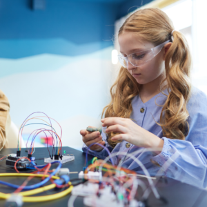 young girl building robotics wearing safety goggles